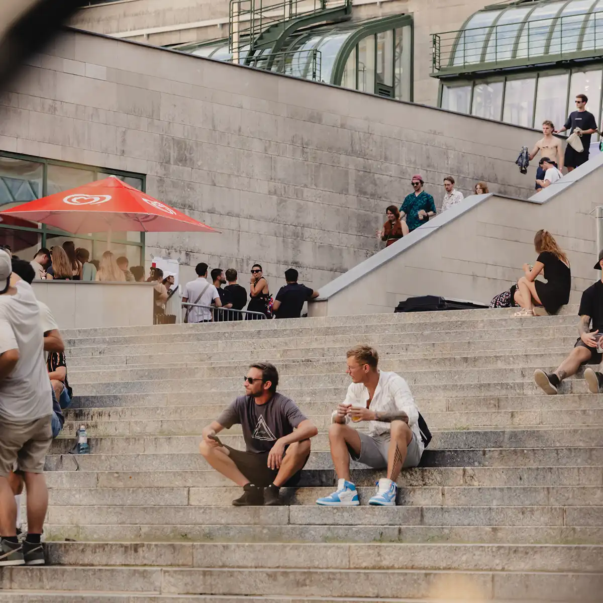 Menschen sitzen auf der Treppe vor einem großen Gebäude und reden miteinander