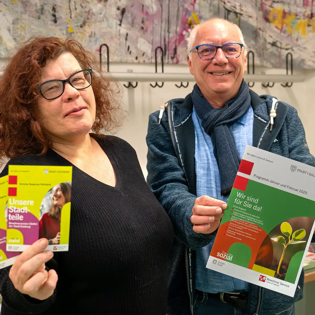 Begegnung BWS Lehen, Zwei Personen die jeweils einen FOlder in der Hand halten und lächeln