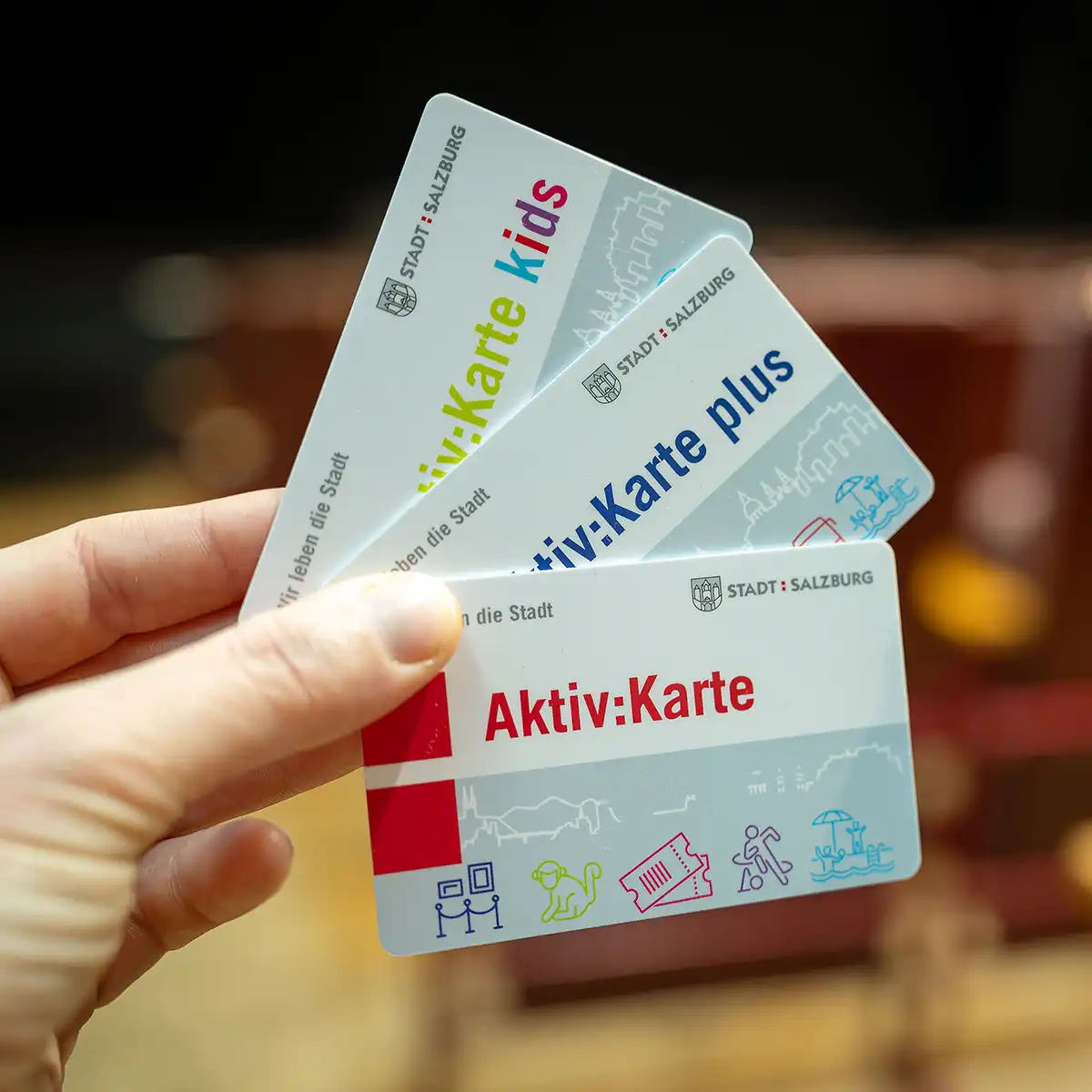 Eine Hand hält die drei verschiedenen Aktiv Karten der Stadt Salzburg