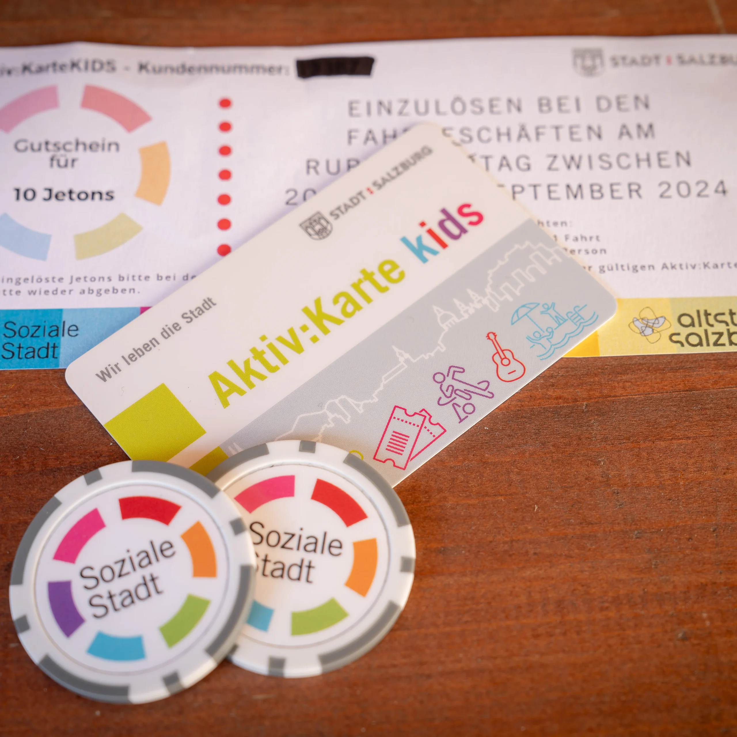 auf einem Tisch liegt eine Aktivkarte, Jetons und ein Gutschein von der Sozialen Stadt Salzburg